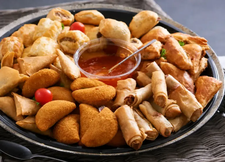 Savoury party platter with pastries, rolls, and dipping sauce by Brie Cakes