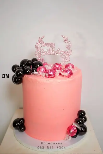 Pink celebration cake with black and red decorations by Brie Cakes